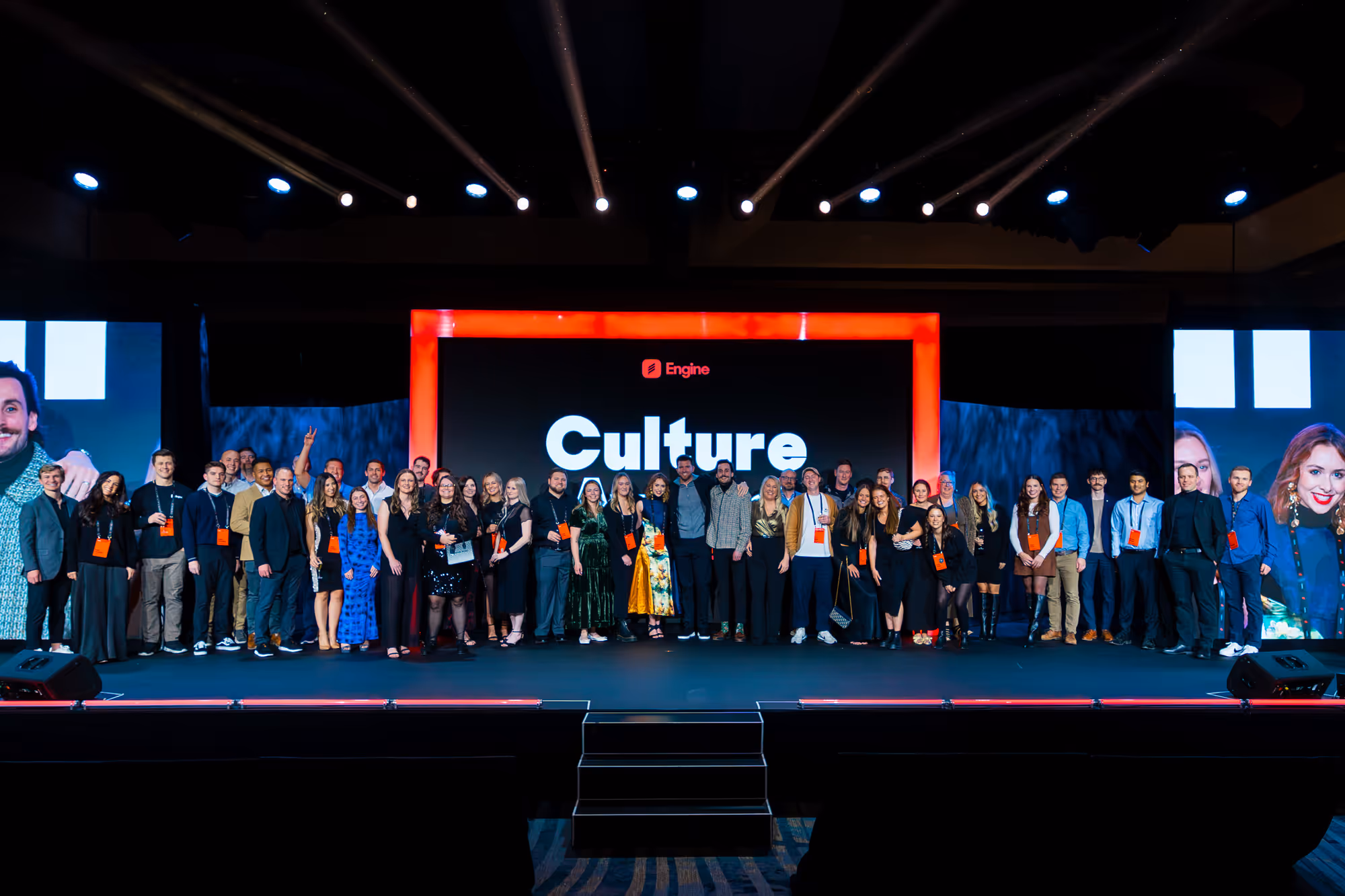 A group of people standing on stage in front of a screen with the word culture on it.